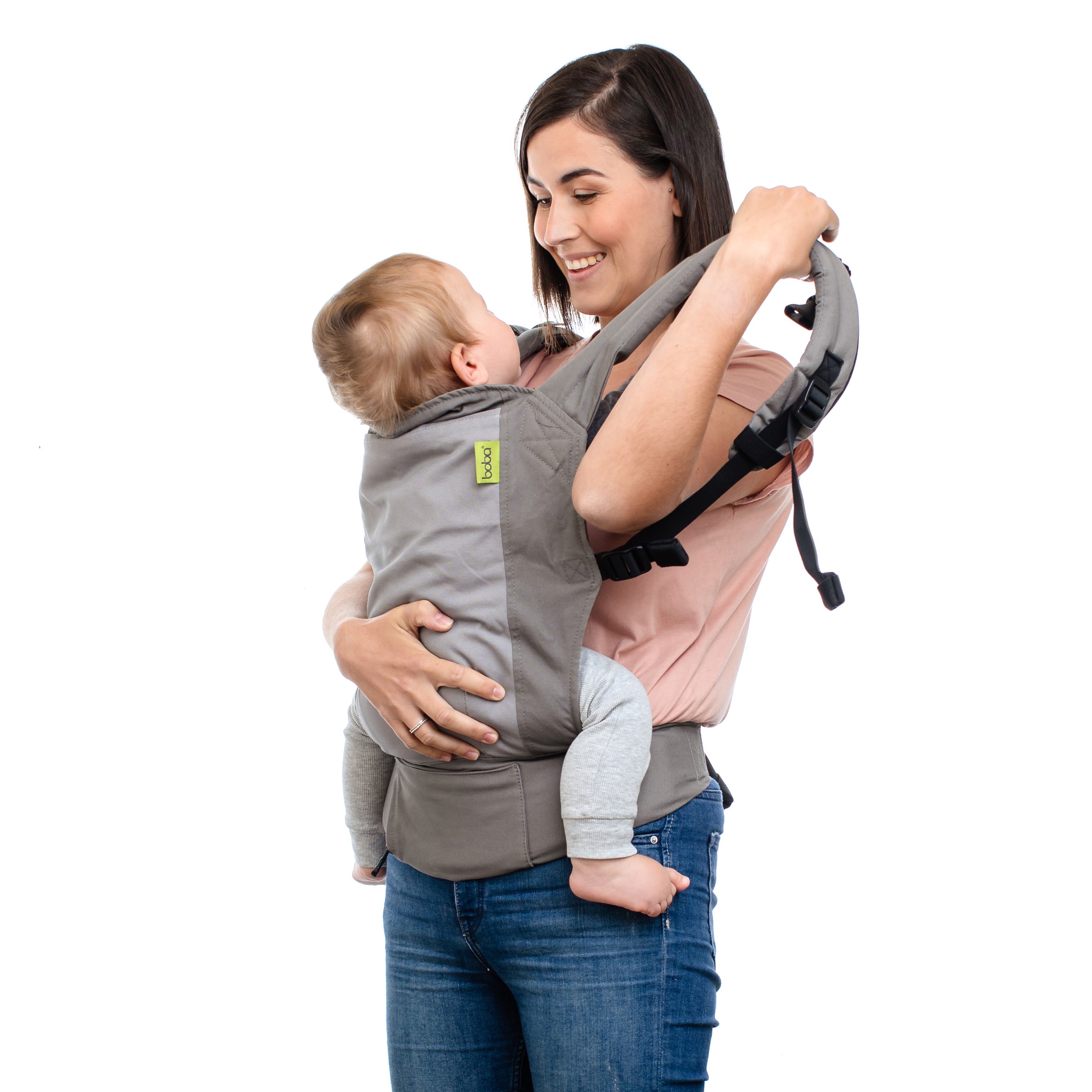 A joyful mama with brown short hair is putting her little boy in the front carry in the gray 4gs dusk infant carrier.