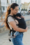 A lightweight, Boba Air Baby Travel Carrier with padded mesh straps, leg openings, adjustable shoulder straps, and an integrated hood. Compact and self-storing, it fits babies 4-24 months (15+ lbs) and children up to 45 lbs,  Black