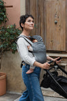 A lightweight, Boba Air Baby Travel Carrier with padded mesh straps, leg openings, adjustable shoulder straps, and an integrated hood. Compact and self-storing, it fits babies 4-24 months (15+ lbs) and children up to 45 lbs, Gray