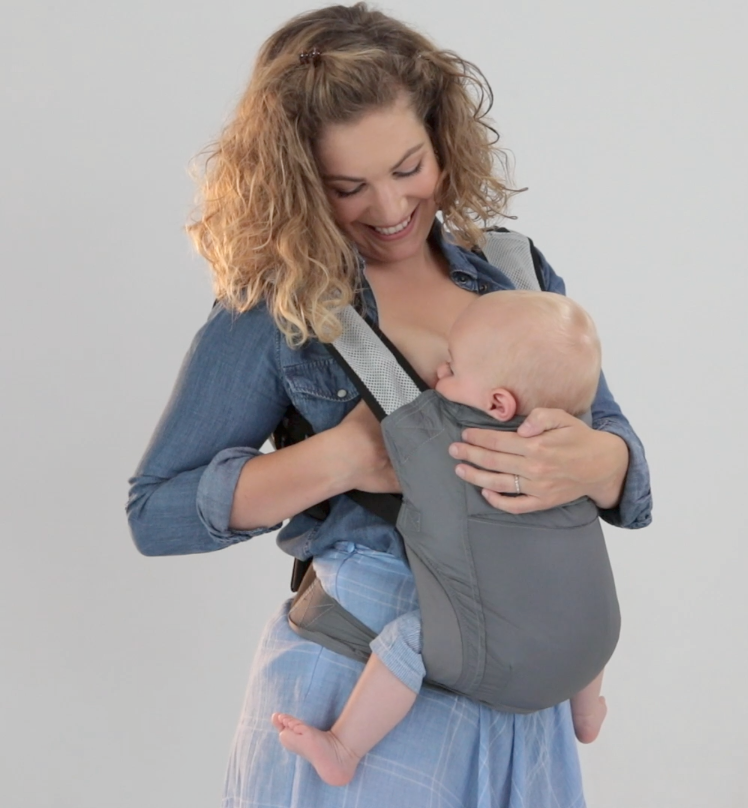 Pleased happy mom looking at her baby lovingly while she nurses her infant daughter in the gray boba air carrier.