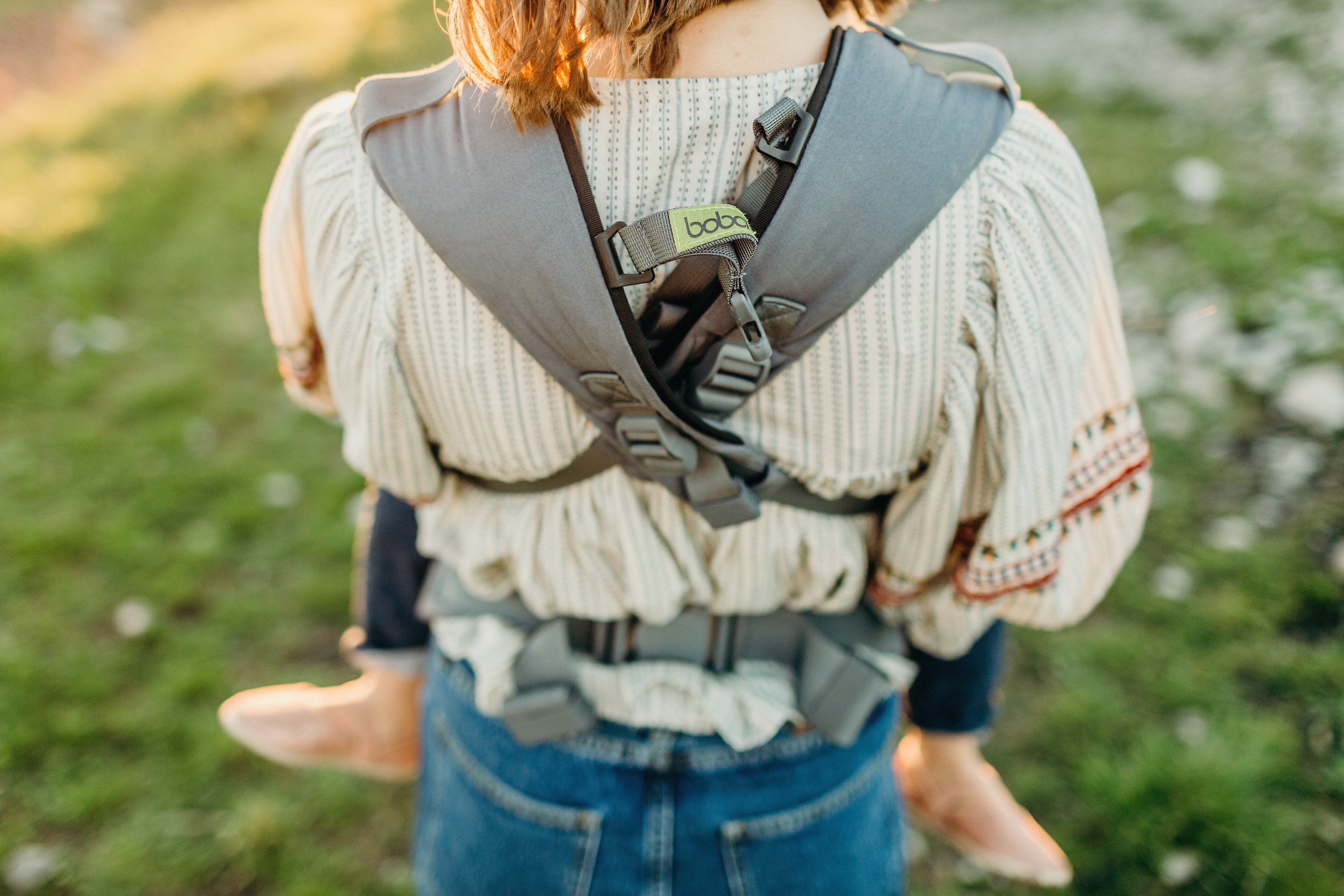 Woman wearing her baby with a crossed straps variaton of the front carry in the gray boba x baby carrier.